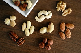 piles of almonds, cashews, brazil nuts, pecans, walnuts, and hazelnuts on wood table
