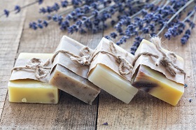 stack of 4 handmade soaps wrapped in brown paper and brown string leaning on each other with lavender stems in the background