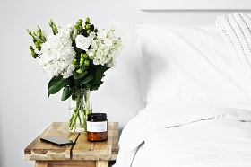white flower bouquet on side table next to bed